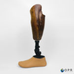 prothèse tibiale de jambe en carbone avec esthétique en bois des motifs u-exist realisé par les prothésistes en bretagne a rennes et en normandie a avranches et saint lo